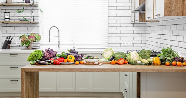 Diverse groenten op een houten tafel tegen de muur van een modern keukeninterieur.