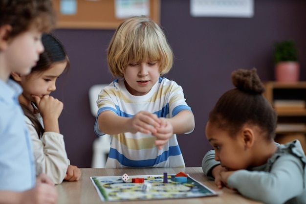 Diverse groep kleine kinderen die samen bordspel spelen in de kleuterschool