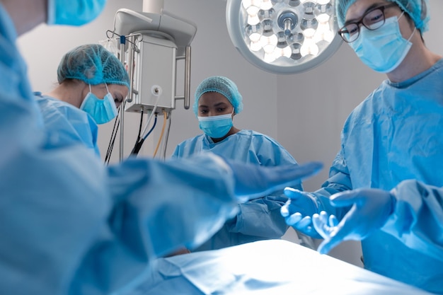 Diverse groep mannelijke en vrouwelijke chirurgen in de operatiekamer die gezichtsmaskers dragen en een operatie uitvoeren