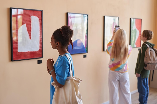 Diverse groep tieners kijken naar abstracte kunst in kunstgalerie