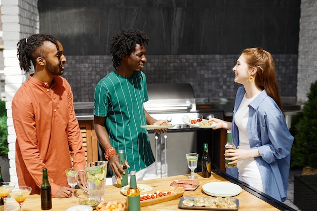 Diverse groep vrienden genieten van diner op terras in zonlicht