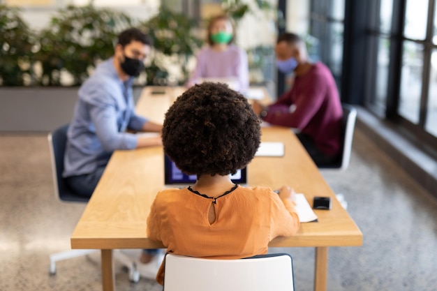 Photo diverse group of business people working in creative office. group of people in a meeting discussing work. social distancing protection hygiene in workplace during covid 19 pandemic.