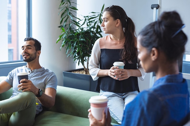 Foto gruppo eterogeneo di colleghi creativi che tengono caffè da asporto, parlano durante una riunione informale. ufficio moderno di un'azienda di design creativo.