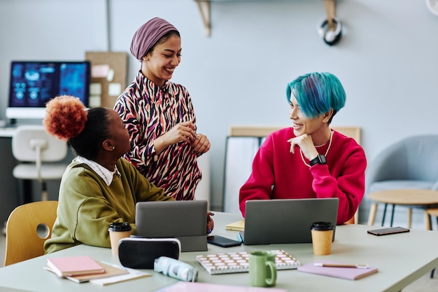 Diverse group of creative young people chatting during meeting in office