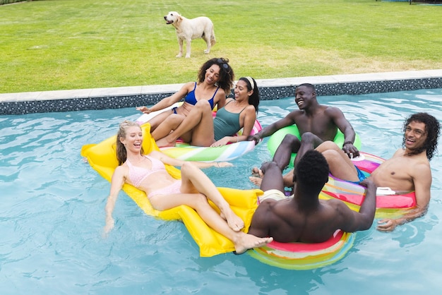 Photo diverse group of friends enjoy a pool party with a dog watching from the grass