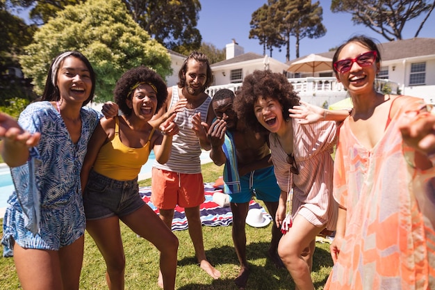 Разнообразная группа друзей веселится и улыбается на вечеринке у бассейна. Прогулки и отдых на свежем воздухе летом.
