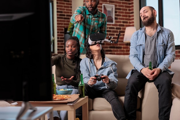 Photo diverse group of friends playing video games with vr glasses, using augmented reality and 3d simulation to play competition. cheerful people enjoying headset and game at house party.