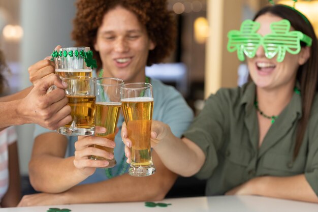 Photo diverse group of happy friends celebrating st patrick's day making toast with glasses of beer at bar