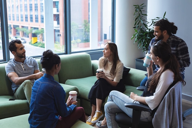 Фото Разнообразная группа творческих коллег, которые пьют кофе на вынос и разговаривают на случайной встрече. современный офис креативного дизайнерского бизнеса.