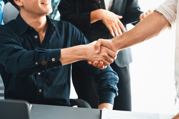 戦略的なビジネスマーケティング会議について合意した後、会社員の多様なグループが握手する チームワークと前向きな姿勢が生産的で協力的な職場を生み出す 賢明