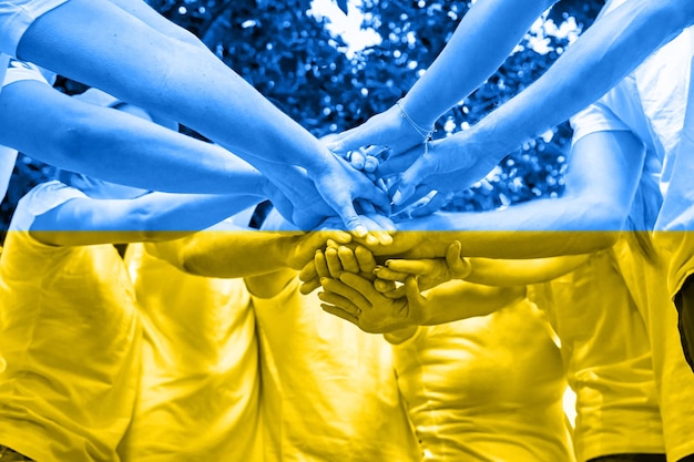 A diverse group of people stacking hands Concept of Ukrainian patriotism on yellowblue flag background War Russia against Ukraine