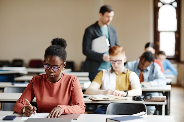 Diverse group of students taking notes in row during lecture in college or university copy space