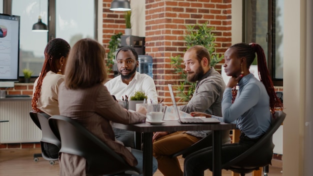 Diverse group of workmates talking about project planning for big startup presentation in office. Team of people working on marketing strategy and company development. Briefing conference