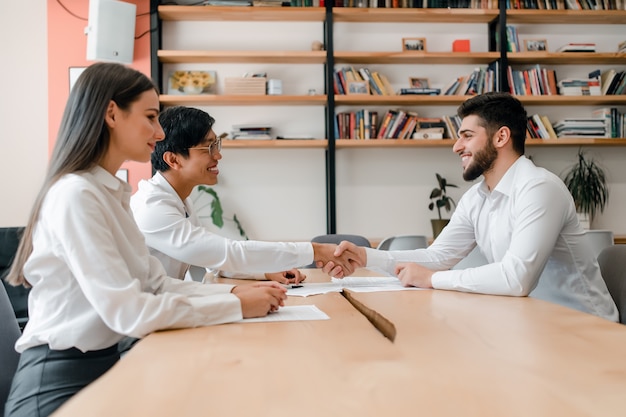 Diverse group of young business people cooperating and shaking hands on a deal in the office