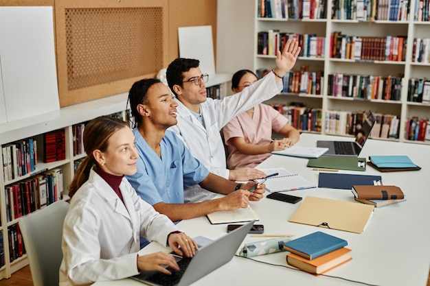 行に座っている若い医学生の多様なグループ