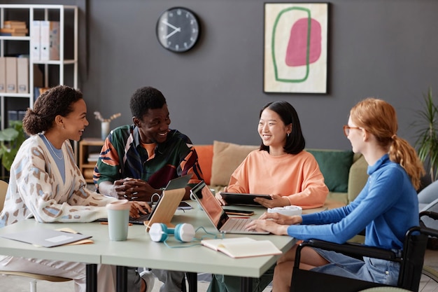 Diverse group of young people laughing happily during meeting in it office