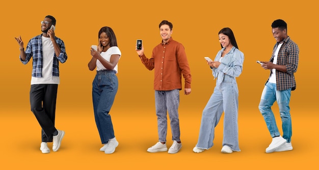 Разнообразные счастливые мультиэтнические люди разговаривают или обмениваются сообщениями на смартфонах на оранжевом фоне