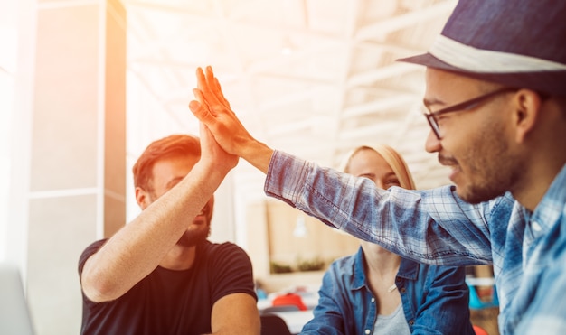 Diverse jonge mannen doen high five in café