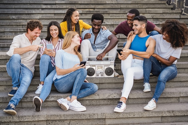 Diverse jonge mensen die plezier hebben met het luisteren naar muziek met boombox stereo buiten in de stad - Focus center african girl face