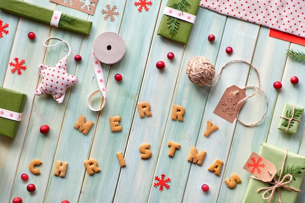 Diverse kerst- of Nieuwjaars eco-vriendelijke decoraties voor de winter, ambachtelijke papieren pakketten en verschillende zero waste-geschenken. Plat op houten planken, tekst "Merry Christmas" gemaakt van koekjes.