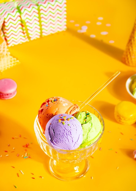 Diverse kleurrijke ijslepels of ballen ijscoupe schotel met wafelkegels bitterkoekjes op gele achtergrond