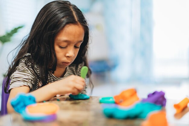 Foto diverse kleuterschoolmeisje thuis speelt met kleurrijke modelleer klei