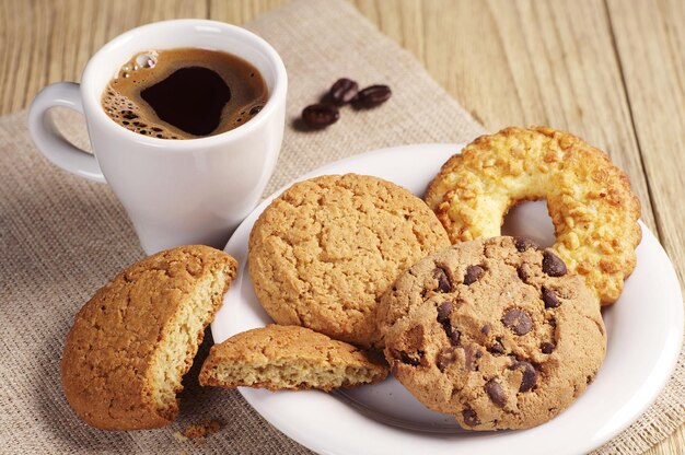 Diverse koekjes en kop warme koffie op houten tafel