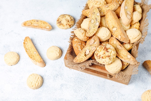 Diverse koekjes in een houten dienblad op grijs