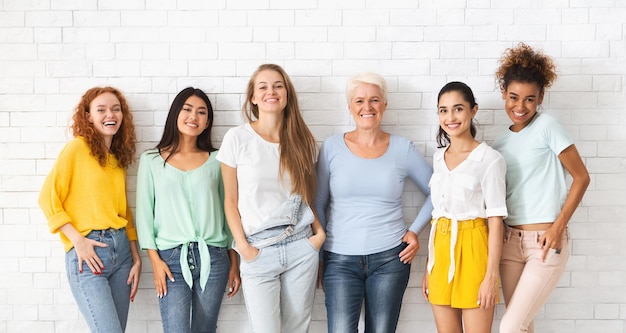 diverse ladies of different age standing over white brick wall