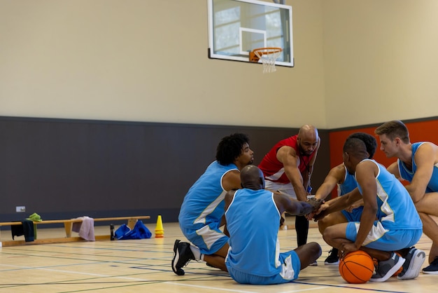 Photo diverse male basketball players teaming up with coach at gym, copy space. sport, activity, togetherness and lifestyle, unaltered.