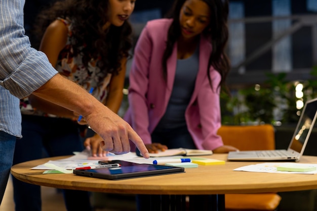 Photo diverse male and female colleagues in discussion using tablet and laptop in casual office meeting. casual office, teamwork, business, communication and work, unaltered.