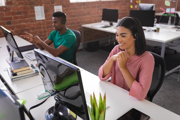 Photo diverse male and female colleagues having video call sitting in front of computers using headphones