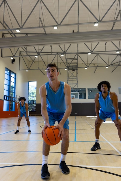 Diverse mannelijke basketbalspelers dragen blauwe sportkleding en schieten basketbal in de sportschool. Sport, activiteit, teamwerk en levensstijl, ongewijzigd, kopieerruimte.