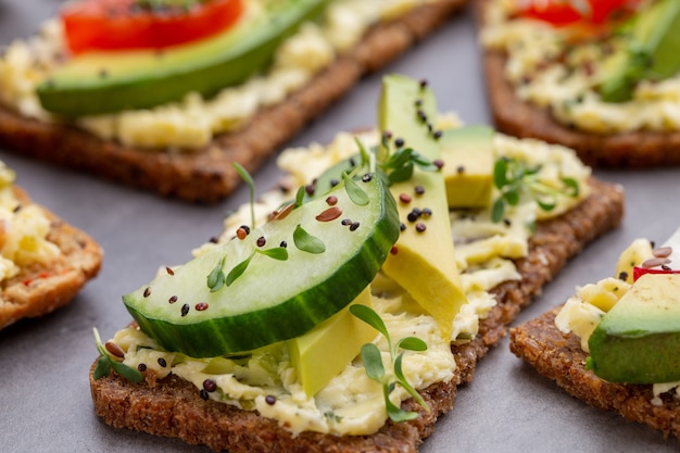 Diverse mini sandwiches met roomkaas, groenten en salami.