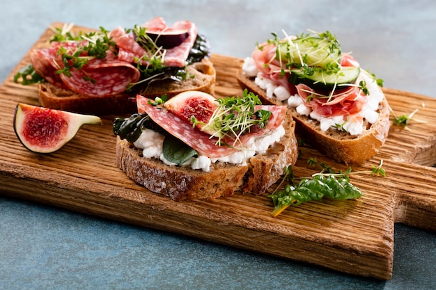 Diverse mini sandwiches met roomkaas, groenten en salami.