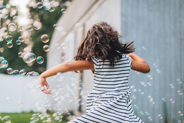 Photo diverse mixed race pre school age girl at home having fun playing with bubbles