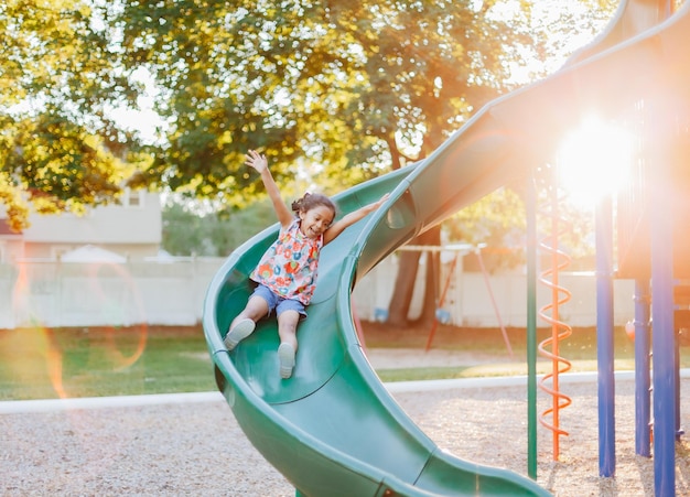 diverse mixed race pre school age girl at park during a nice summer sunset afternoon having fun on playground being happy and creating childhood memories