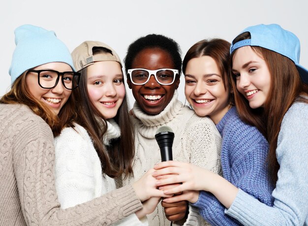 Diverse multi nation girls group teenage friends company cheerful having fun with microphone