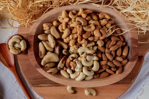 Foto diverse noten in een houten kom en in twee houten kopjes met stro achtergrond. hoofdnoten van de braziliaanse keuken.