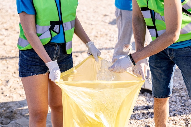 Diverse people cleaning up the beach volunteers collecting the waste on the coast line