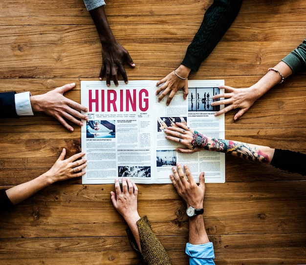 Photo diverse people hands reach out for hiring newspaper announcement