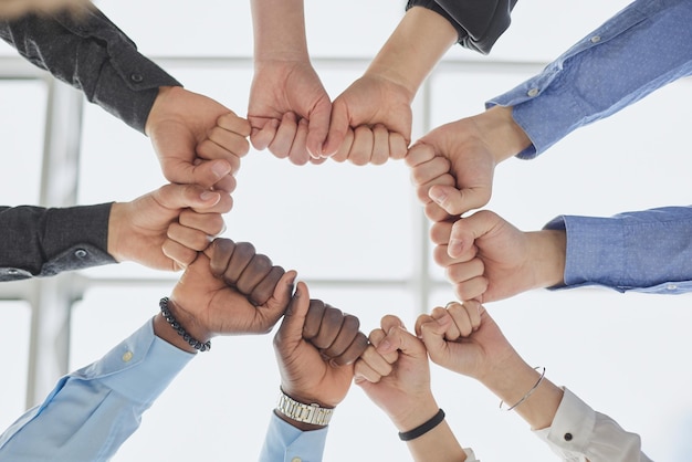 Diverse people holding their fists together in the office