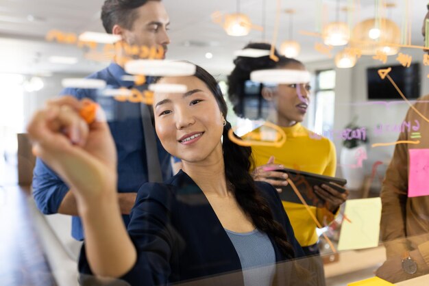 Diverse people in office brainstorming and writing on glass board. Business, corporation, working in office concept.