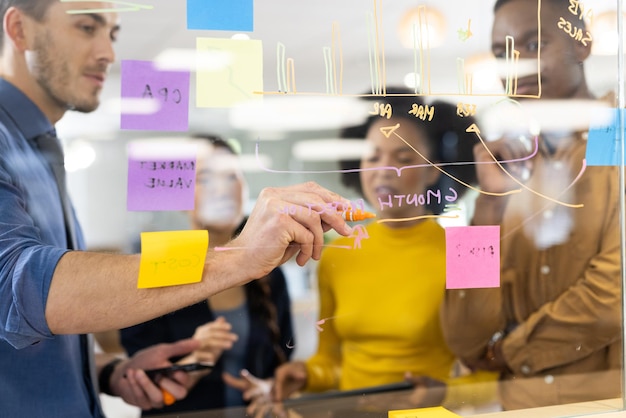 Diverse people in office brainstorming and writing on glass board