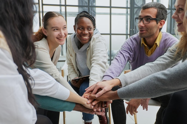 Diverse people sitting in circle holding hands at group therapy