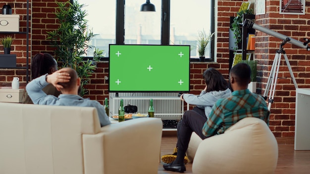 Разные люди переключают телеканалы на шаблон зеленого экрана, смотрят телевизионную программу и смотрят на изолированный фон хроматического ключа. Использование пустого макета copyspace. Съемка со штатива.