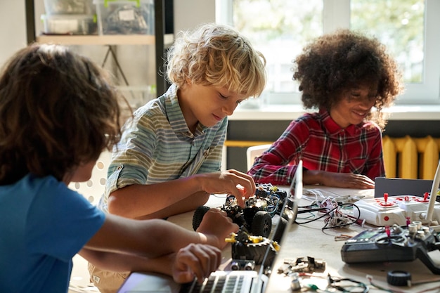 Photo diverse schoolkids building robotic technologies at stem educational class