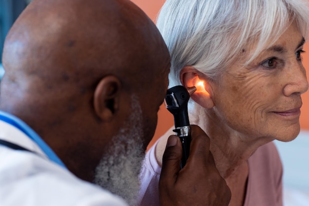 Foto diversi medici senior di sesso maschile che utilizzano l'otoscopio esaminando l'orecchio di una paziente senior sorridente, spazio per la copia. servizi ospedalieri, medici e sanitari.