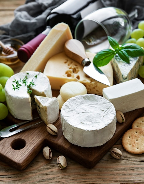 Diverse soorten kaas, druiven en wijn op een houten tafel