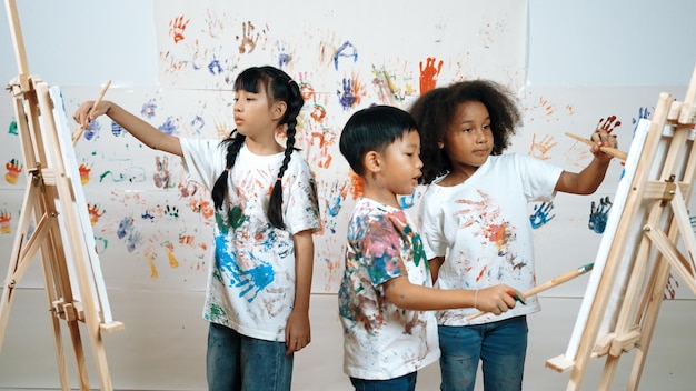 Различные студенты рисовали или рисовали полотно на окрашенной стене на уроке искусства Эрудиция